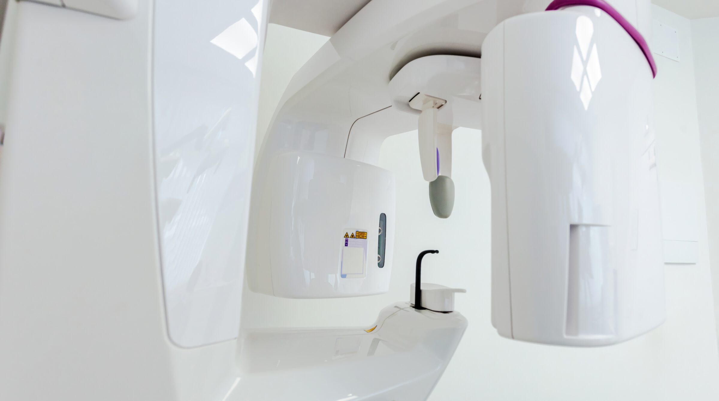 A dental cone-beam CT scanner in a bright clinic room (stock photograph, not the practice’s equipment)
