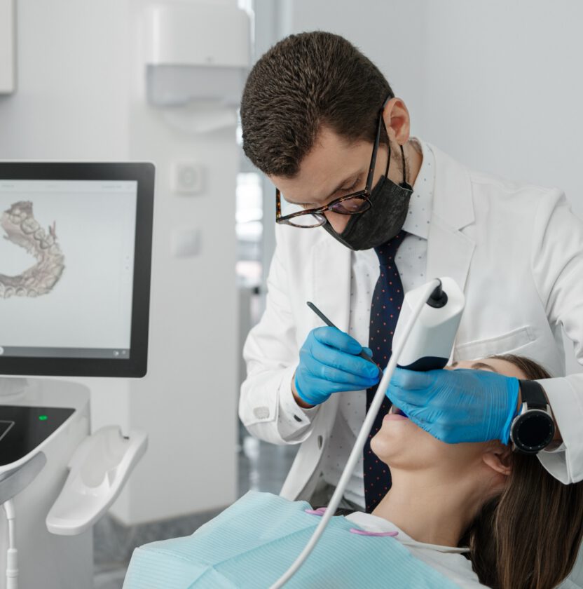 Dentist using a handheld intraoral scanner on a patient, with the 3D scan shown on a screen